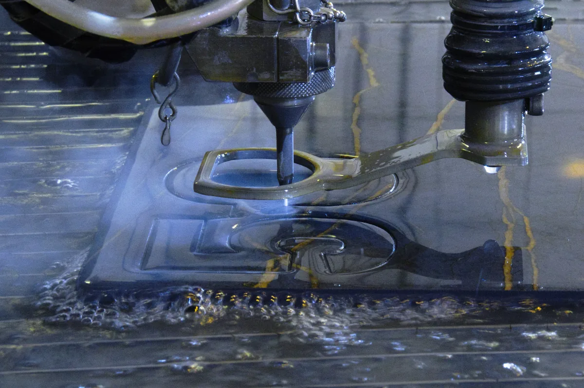 Snijkop snijdt glas onder water; de straal trekt een wolk door het bad.