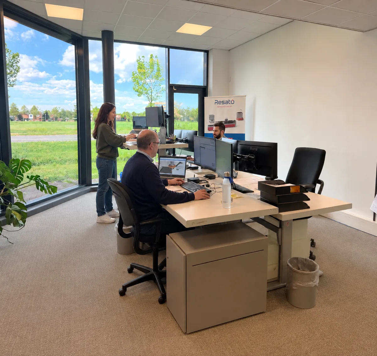 Des collègues au travail dans le bureau d'Assen, avec vue sur la zone d'activité.