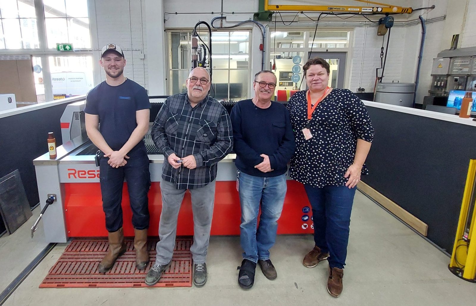 Four people beside the newly delivered Resato waterjet cutting machine in the workshop